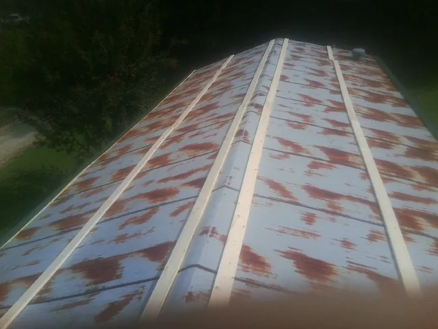 Rusted metal roof panels with new wood purlins before replacement — Storm Damage Roof Repair in Six Lakes by Roofing Brothers