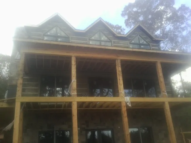 Dormers and porch framing on a large log home under construction — Roof Coating work by our crew in Six Lakes
