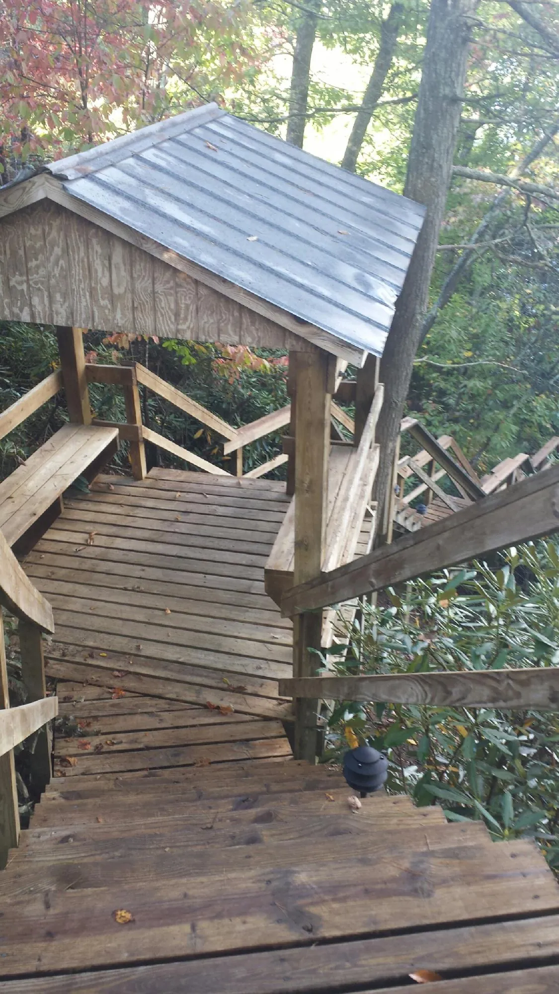 Metal roofed shelter over wooden steps on a wooded walkway — Skylight Repair & Installation work by our crew in Six Lakes