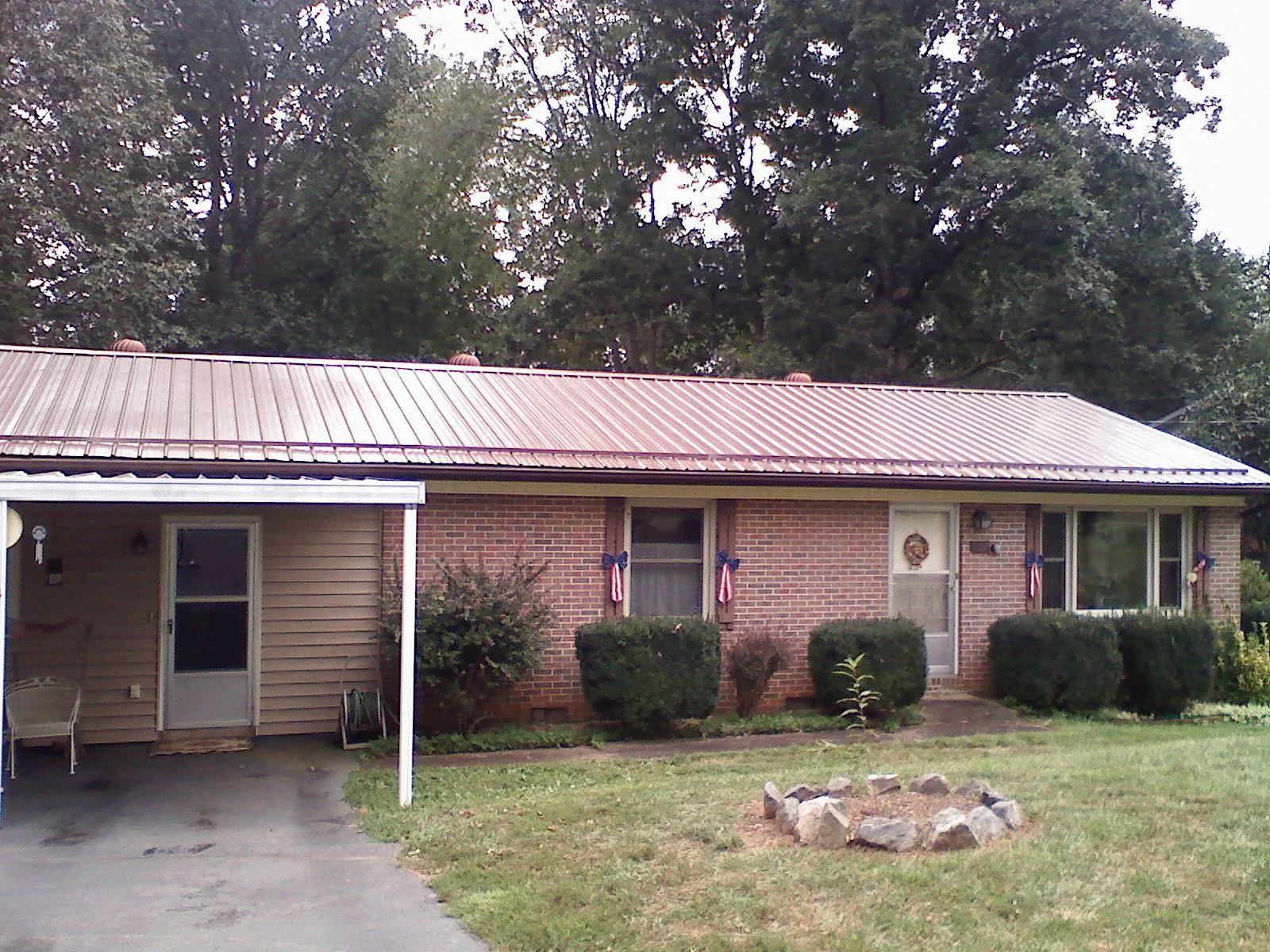 Bronze metal roof and carport on a brick ranch home — Roof Repair work by our crew in Six Lakes